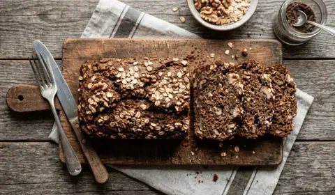 Pan de plátano con avena y cacao en rebanadas sobre tabla de madera
